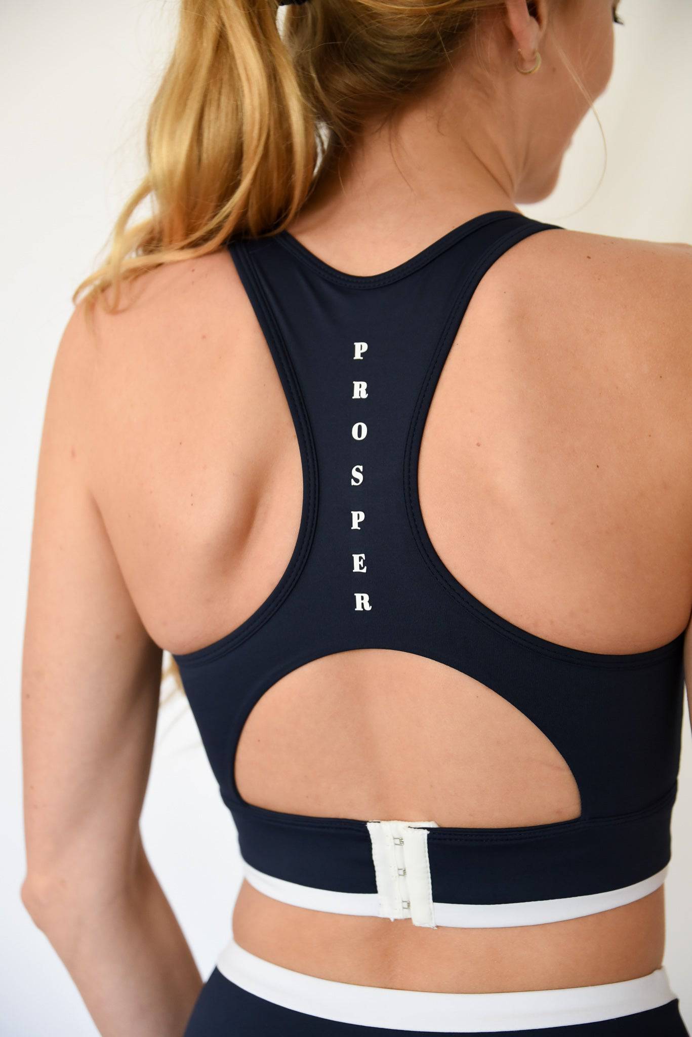 Contender Bra in Navy from back view with "Prosper" written vertically between shoulder blades with up close view